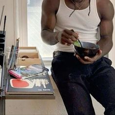 a man sitting on a table holding a bowl