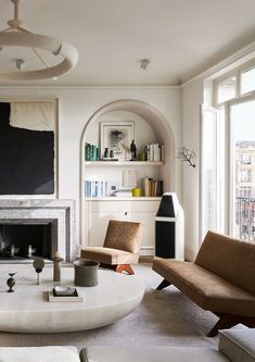 a living room filled with furniture and a fire place in front of a large window