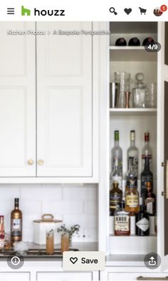 a kitchen with white cabinets and lots of bottles