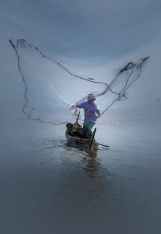 a man on a small boat in the water with a fishing net over his head