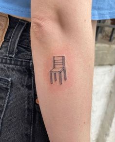 a small chair tattoo on the left arm