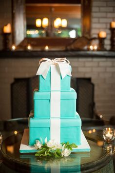 a blue and white cake sitting on top of a table with candles in the background