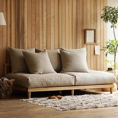 a living room with wood paneling and pillows on the couch in front of a window