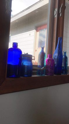 there are many blue glass bottles on the window sill in front of the mirror