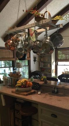 a kitchen filled with lots of pots and pans hanging from the ceiling next to a counter