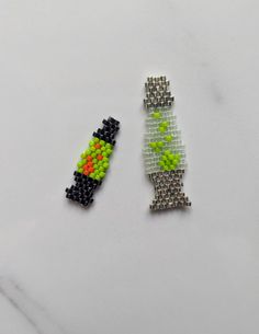 two pieces of beaded jewelry sitting on top of a white table next to each other