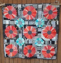 a quilted wall hanging with red and blue flowers