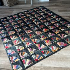 a quilted area rug on the floor in a room with wooden floors and chairs