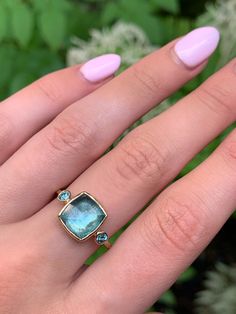 a woman's hand with pink manicured nails and an aqua blue ring