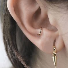 a close up of a person's ear wearing gold earrings