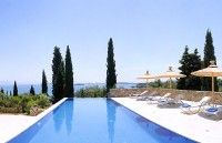 an empty swimming pool with lounge chairs and umbrellas near the water's edge