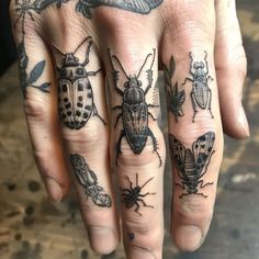 a person's hand with tattoos on it and some bugs in the middle of their fingers