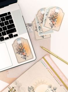 a laptop computer sitting on top of a desk next to notebooks and paper with stickers