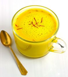 a glass cup filled with liquid next to two spoons