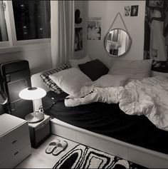 black and white photograph of an unmade bed in a room with pictures on the wall