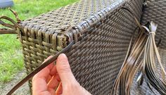 a person is holding a piece of wire in their hand near a wicker bench