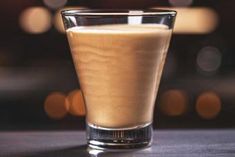 a glass filled with liquid sitting on top of a table next to a blurry background