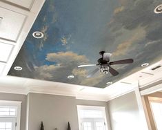 a ceiling with clouds painted on it in a room that has white walls and windows