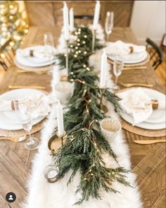 a dining room table decorated for christmas with candles and greenery