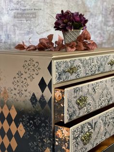 an ornate dresser with flowers on top and decorative wallpaper in the backgroun