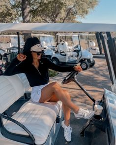 a woman is sitting in the driver's seat of a golf cart