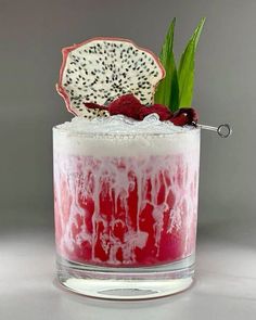 a drink with fruit and ice on the rim, garnished with green leaves