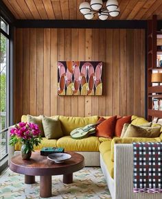 a living room filled with lots of furniture and wooden paneling on the wall behind it