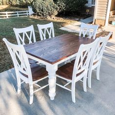 a wooden table and white chairs on concrete