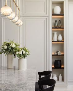 two vases with flowers sit on a marble table