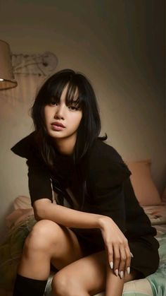 a young woman sitting on top of a bed next to a lamp in a room