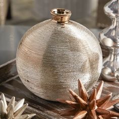 a silver vase sitting on top of a wooden table next to other glass and metal objects