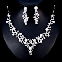 A classy bridal necklace and earrings set, perfect for the romantic bride! Adorned with iridescent pearls and clear crystals that capture the light from every angle sparkling beautifully, the pieces are rhodium plated for a flawless finish which enhances the intricate detailing and conveys a modern take on old elegance. Necklace: 16" long (approx. 41cm) with a 2.5" extension chain (approx. 6.5cm) which allows the length to be adjusted to 18.5" (approx. 47.5cm). If you would like it longer, pleas White Pearl Jewelry With Sparkling Stones, Elegant Silver Pearl Jewelry Sets, Elegant Crystal Jewelry Sets With Pearl Drop, Elegant White Crystal Jewelry Sets, Silver Cubic Zirconia Pearl Necklace For Parties, White Pearl Jewelry With Rhinestones, Silver Pearl Necklace With Rhinestones For Wedding, Silver Crystal Jewelry Set With Pearl Drop, Elegant Silver Rhinestone And Pearl Necklace