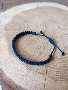 a blue string bracelet sitting on top of a piece of wood