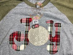 a gray and green shirt with the word joy written in red, white, and black letters