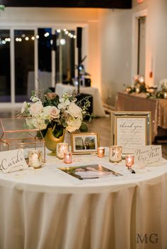 a table topped with pictures and candles on top of a white table cloth covered table