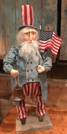 a statue of santa claus holding an american flag and a potted hat on top of a wooden table