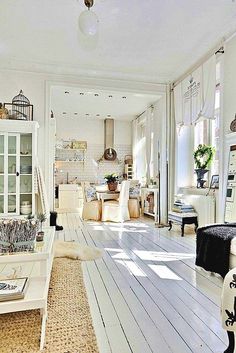 a living room filled with white furniture and lots of light coming in from the windows