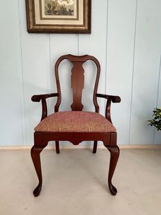 an old fashioned wooden chair sitting in front of a painting