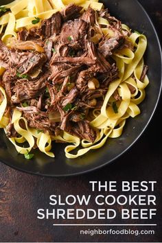 the best slow cooker shredded beef recipe is in this black plate on a wooden table