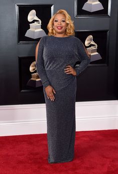 a woman standing on top of a red carpet in front of a group of awards