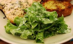 a white plate topped with lettuce and fish next to french toasted bread