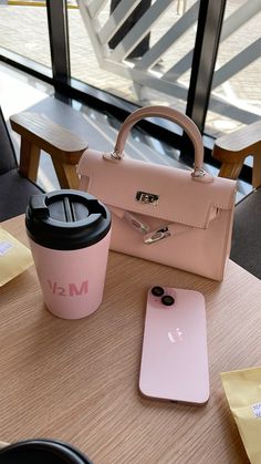 a coffee cup, cell phone and purse on a table