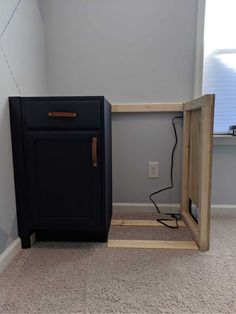 a black cabinet sitting next to a window in a room with carpeted flooring