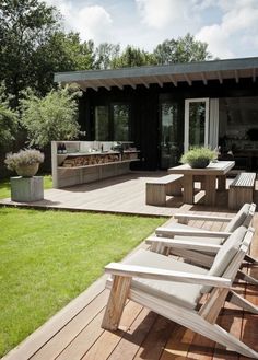 a wooden deck with lawn chairs and an outdoor bbq in the back ground area