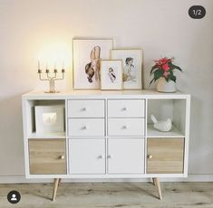 a white cabinet with drawers and pictures on the top, next to a candle holder