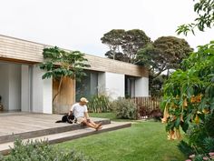 a man sitting on the steps in front of a house with trees and plants around him