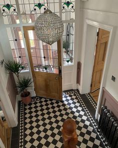 an entryway with a black and white checkered floor, chandelier and wooden door