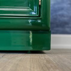 the bottom part of a green cabinet with wood flooring