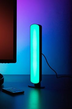 a computer monitor sitting next to a blue and green light on top of a desk