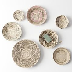 six woven plates arranged on top of each other in different patterns and sizes, with a green object between them